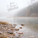 Serene Misty Lake Landscape with Rocky Shoreline and Autumn Foliage