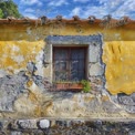 Charming Rustic Window with Flower Pots on Weathered Yellow Wall