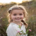 Joyful Child in Nature: Smiling Girl with Flower in Hair, Outdoor Portrait