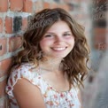 Natural Smiling Portrait of Young Woman Against Brick Wall