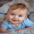 Adorable Baby with Bright Blue Eyes Smiling on Cozy Blanket