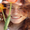 Joyful Young Woman with Freckles and Flowers in Soft Focus - Natural Beauty and Spring Vibes