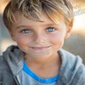 Charming Young Boy with Bright Blue Eyes and Freckles Smiling Outdoors