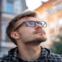 Thoughtful Young Man in Glasses Looking Upwards in Urban Setting