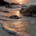 Serene Sunset Over Ocean Waves and Rocky Shoreline