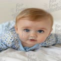 Adorable Baby with Bright Blue Eyes Crawling on Soft Bedding