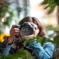 Creative Photography: Young Woman with DSLR Camera Surrounded by Greenery