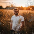 Young Man in White T-Shirt Standing in Golden Field at Sunset