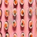 Rolês de Sushi Coloridos em Fundo Rosa com Hashis - Delícia da Culinária Japonesa