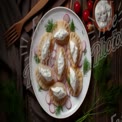 Delicious Homemade Dumplings with Sour Cream and Fresh Herbs on Rustic Table