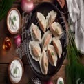 Delicious Homemade Dumplings with Sour Cream and Fresh Herbs on Rustic Wooden Table