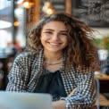 Cheerful Young Woman in Cozy Cafe with Laptop, Embracing Creativity and Connection