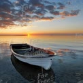 Tranquil Sunset Over Calm Waters with Rowboat Reflection