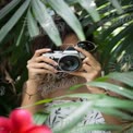 Capturing Nature: Woman with Camera Surrounded by Lush Greenery