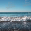 Tranquil Ocean Waves on Serene Beach Under Clear Blue Sky