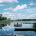 Tranquil Lake View with Dock and Reflections Under Blue Sky