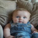 Adorable Baby with Bright Blue Eyes in Denim Overalls