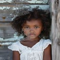 Portrait of a Thoughtful Young Girl with Curly Hair Against Rustic Background