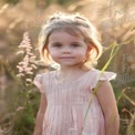 Charming Young Girl in Sunlit Meadow: Innocence and Nature