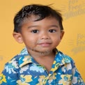 Cheerful Young Boy in Colorful Hawaiian Shirt Against Bright Yellow Background