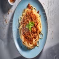 Delicious Spaghetti Bolognese with Fresh Basil on a Blue Plate