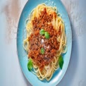 Delicious Spaghetti Bolognese with Fresh Basil on a Blue Plate