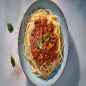 Delicious Spaghetti Bolognese with Fresh Basil on a Light Blue Plate