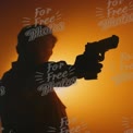 Silhouette of a Person Holding a Gun Against an Orange Sunset