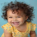 Joyful Toddler with Curly Hair Smiling Against Blue Background