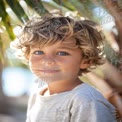 Charming Young Boy with Curly Hair and Bright Blue Eyes in Natural Outdoor Setting