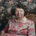 Elegant Senior Woman in Vintage Floral Dress Against Classic Wallpaper