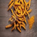 Fresh Turmeric Roots and Powder on Rustic Wooden Background