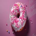 Leckerer rosa glasierter Donut mit bunten Streuseln auf einem lebhaften Hintergrund