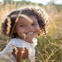 Joyful Child in Sunlit Meadow: Natural Smiles and Childhood Happiness