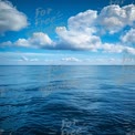 Tranquil Ocean Horizon with Blue Sky and Fluffy Clouds