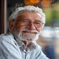 Joyful Elderly Man with Glasses Smiling in a Cozy Cafe Setting