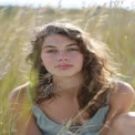 Natural Beauty in a Sunlit Field: Portrait of a Young Woman with Curly Hair