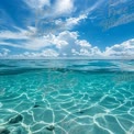 Crystal Clear Tropical Ocean Water Under Blue Sky with Fluffy Clouds