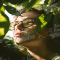 Serene Portrait of a Woman in Nature with Glasses, Sunlight and Green Leaves