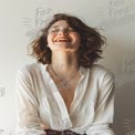 Joyful Woman Smiling in Casual White Shirt Against Neutral Background